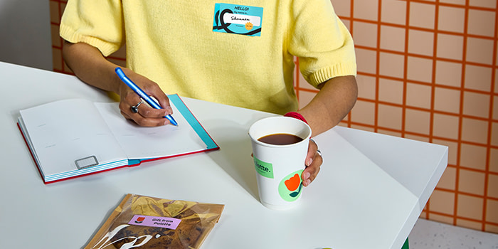 Person writing on Notebook on desk.