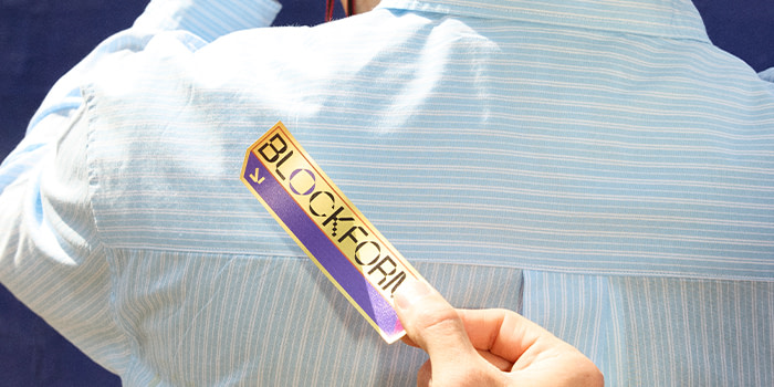 Someone holding up a branded Die Cut Sticker against the back of someone else's shirt.