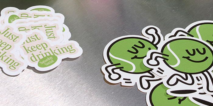 Green Die Cut Stickers displayed on a grey, metallic surface.