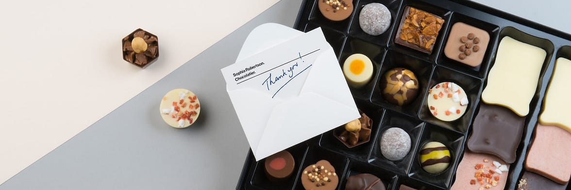 Thank you handwritten note in envelope on a box of chocolates