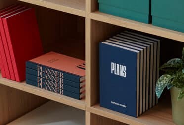 Branded Perpetual Planners displayed on wooden bookshelf.