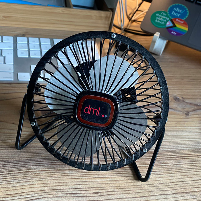 A USB-powered fan on a desk from a marketing agency called DML.