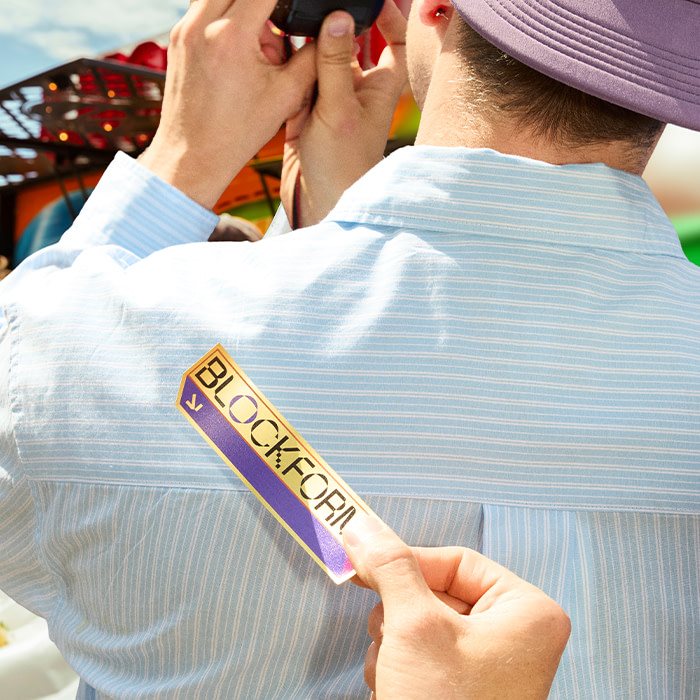Someone taking a phot outside with a sticker being held behind them.