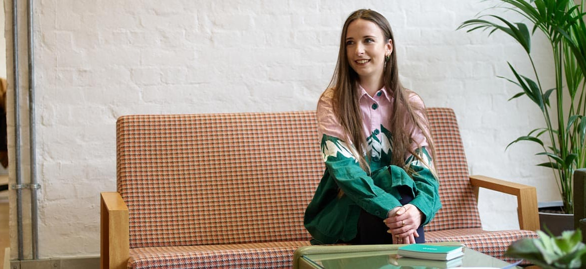 Ellie Shenton, graphic designer at MOO, sat on a couch in the MOO London office