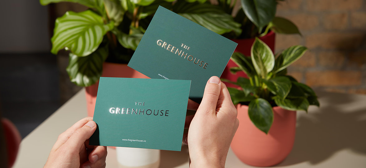 Customer holding two green Postcards with Gold Foil finish on logo.