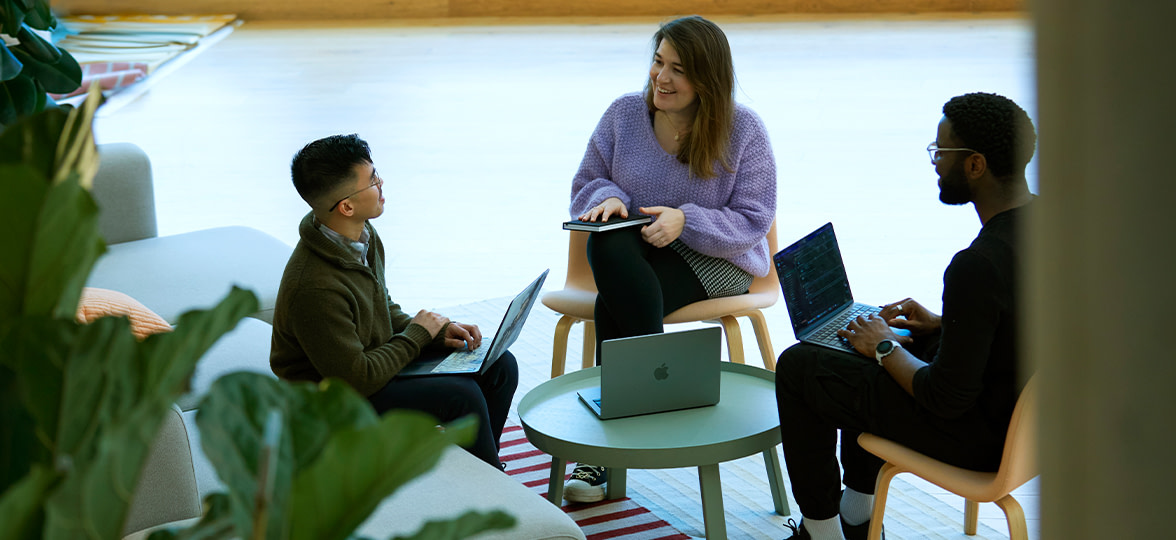 Three people having a meeting with laptops and notebooks