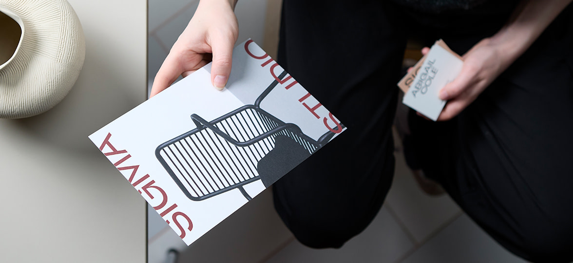 A person holding MOO business cards and a postcard