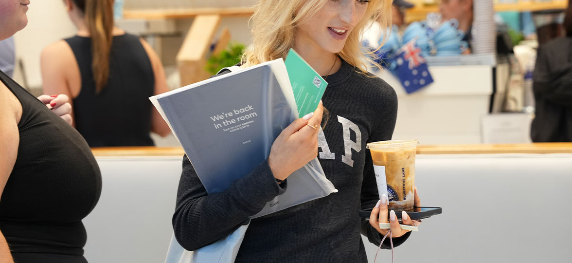 Woman holding coffee and MOO Softcover Notebook.