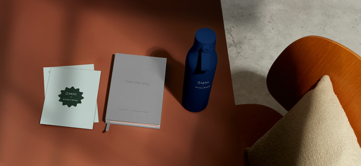 A branded Water Bottle, Notebook and Insert on a brown desk.