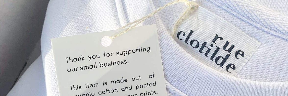 Close-up of Rue Clotilde white tshirt with hang tag explaining the sustainable production process