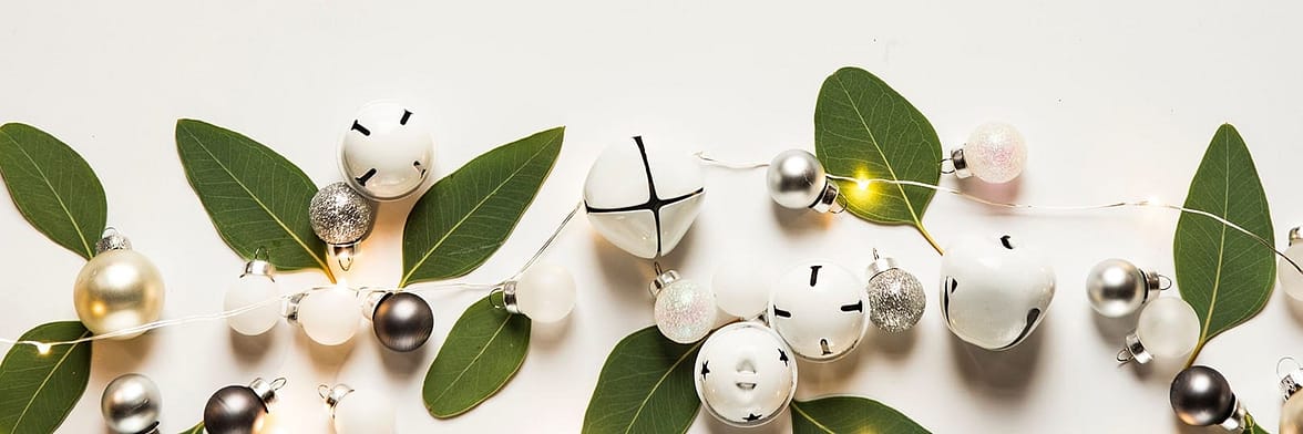 Leaves, bells, and white Christmas baubles on a white background