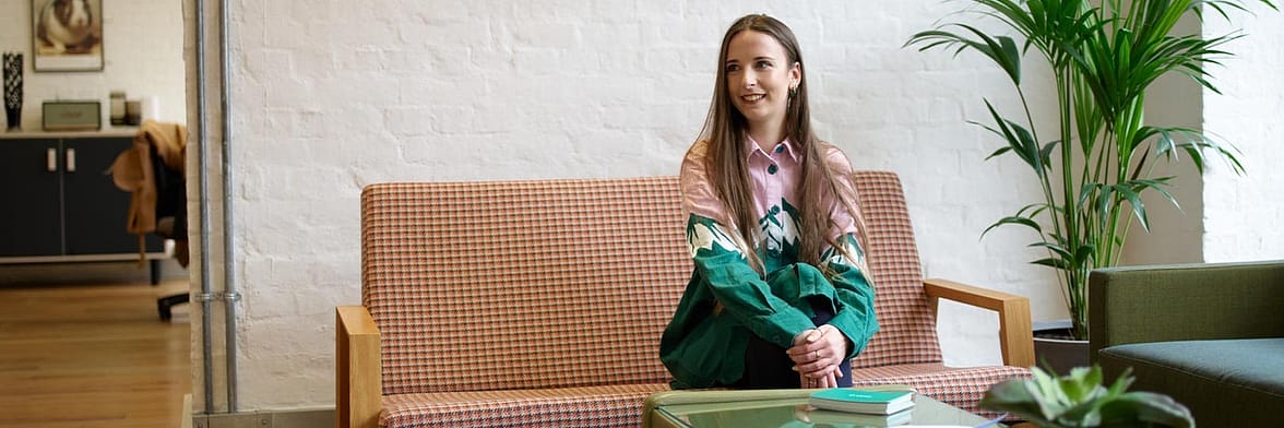 Ellie Shenton, graphic designer at MOO, sat on a couch in the MOO London office
