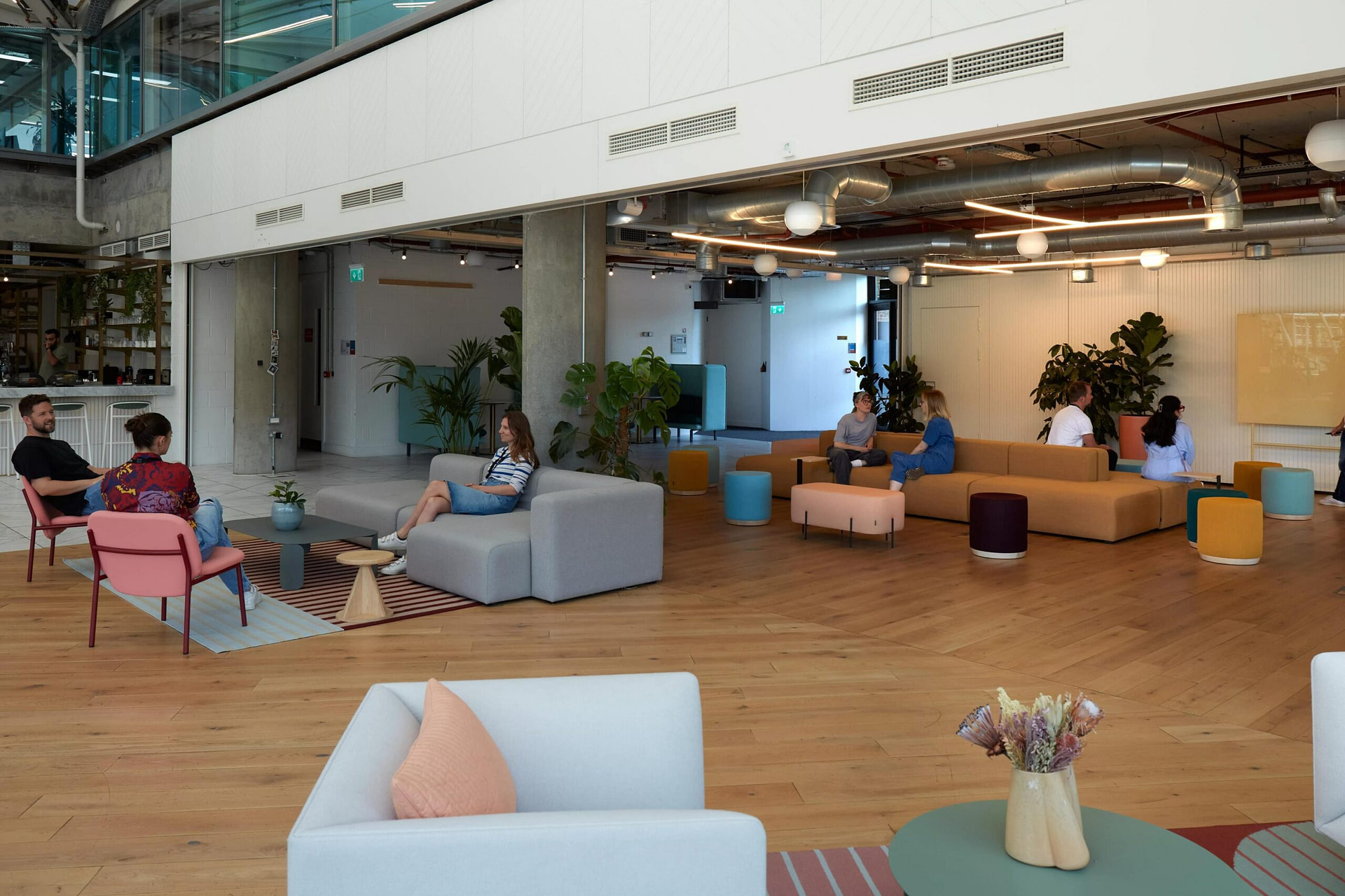 Employees sitting on different sofa spaces having chats with colleagues.