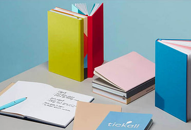 Colorful hardcover notebooks, softcover journals, custom notebooks, branded journals and open notebook with handwritten notes and pen