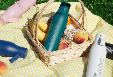 Custom water bottles with logos on a summer picnic blanket