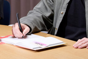 Someone taking notes during a meeting in a notebook