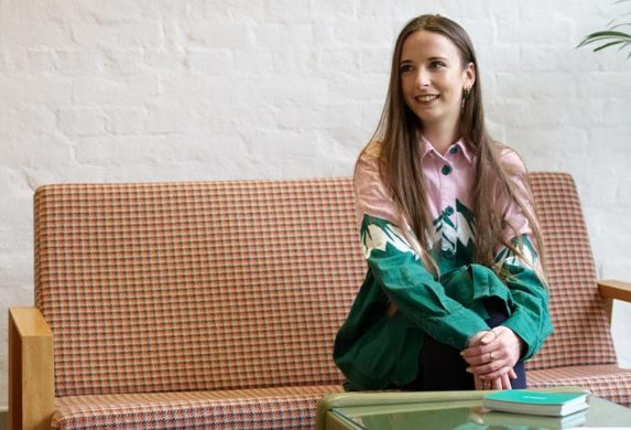Ellie Shenton, graphic designer at MOO, sat on a couch in the MOO London office
