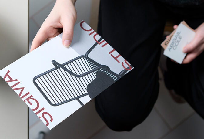 A person holding MOO business cards and a postcard