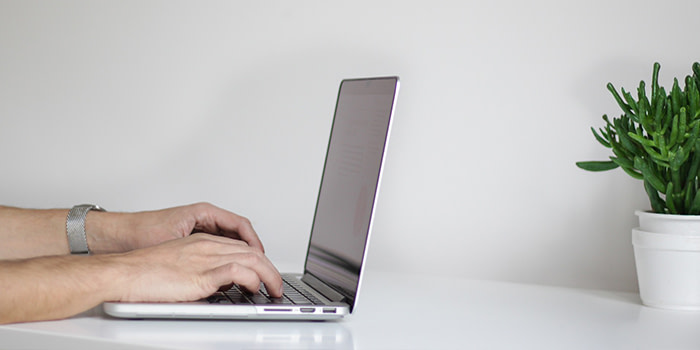 man typing on his laptop with neutral background for video call