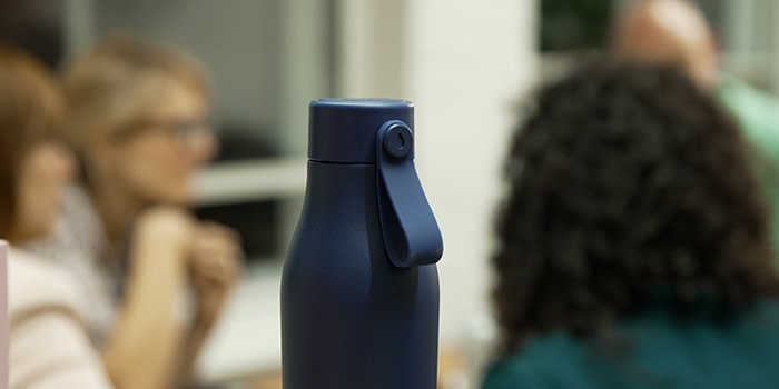 Blue MOO Water Bottle with people in the background