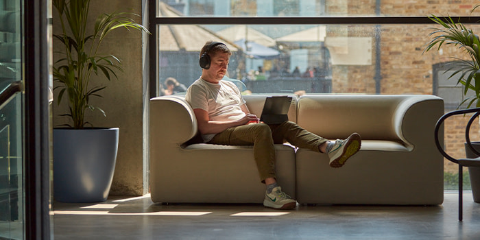 Employee working on sofa, wearing headphones.