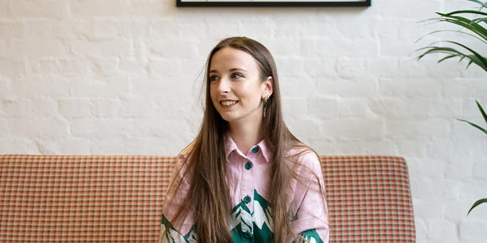 Ellie Shenton, graphic designer at MOO, sat on a couch in the MOO London office