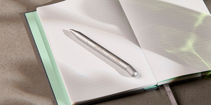 A MOO Twist Pen lying on a notebook