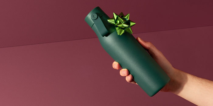 A hand holding a green water bottle with a bow on it.