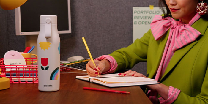 Person working on desk with MOO Water Bottle.