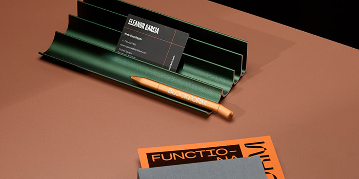 Branded MOO Twist Pen and Business Card displayed in a pen holder on a desk.