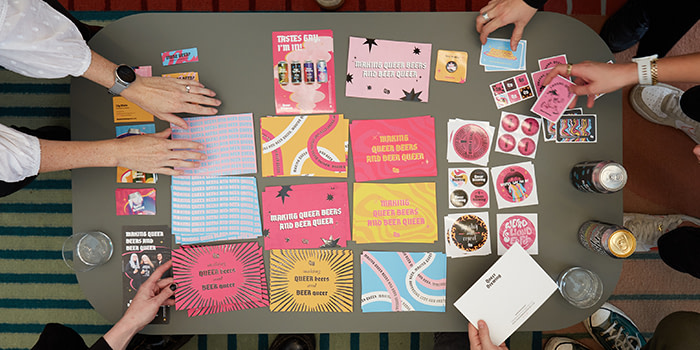 A table featuring Queer Brewing Luxe Business Cards, Stickers, Postcards
