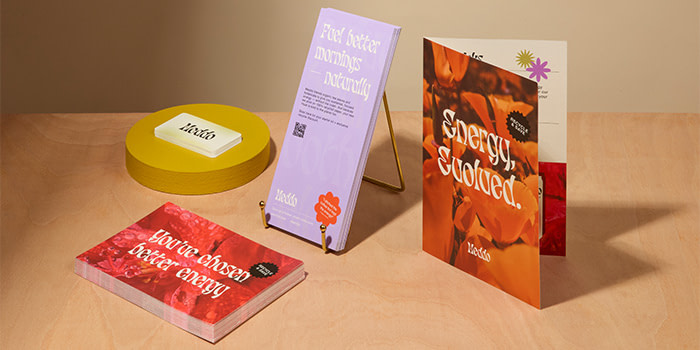 Branded Flyers, Notecards, Business Cards and a notecard displayed on a brown desk.