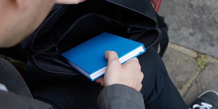 Person putting Notebook away in backpack.