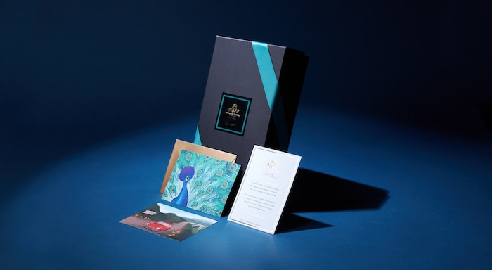 Peacock and Volkswagen Beetle postcards, gold envelope and taste notes card on a wine box
