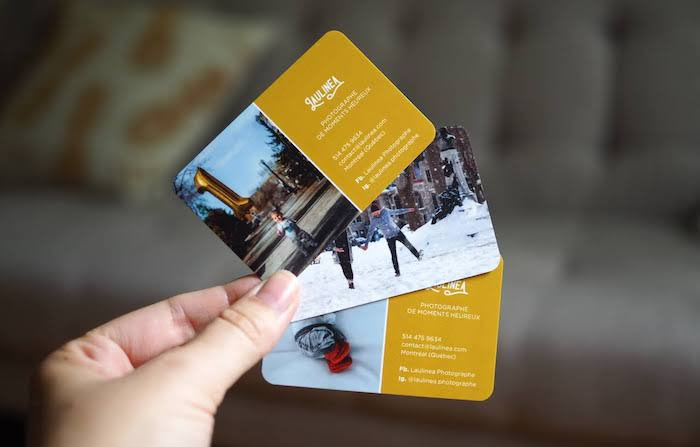 Hand holding three photography business cards by French photographer Laulinéa