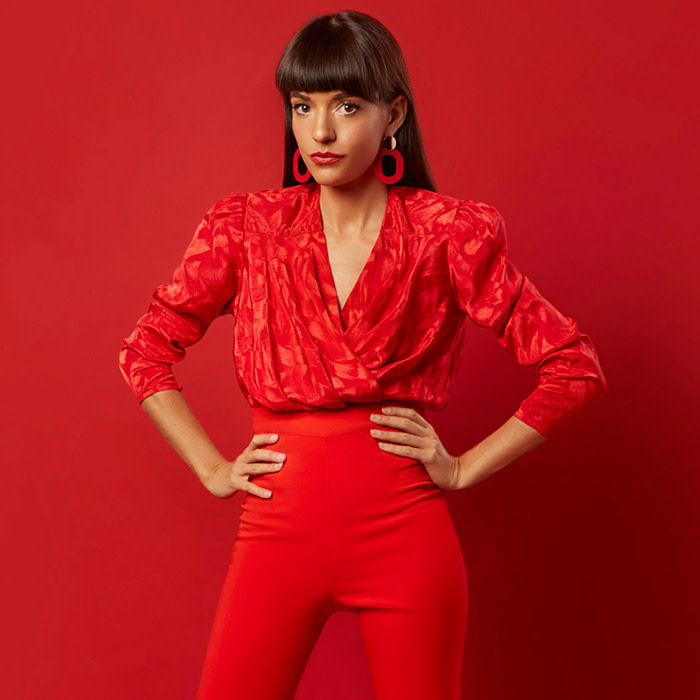 Jessica Walsh female graphic designer in red standing proud against a red background for a photoshoot
