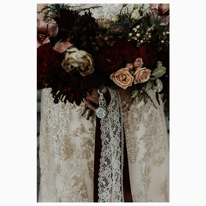 Dark goth-inspired flower bouquet held by a bride with a lace and glitter wedding dress
