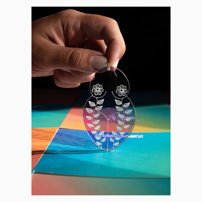 Hand holding a Mackbecks woman-shaped acrylic earring by the top