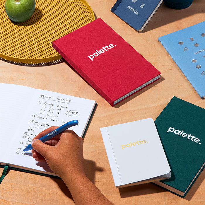 Someone writing a brand launch checklist in a Notebook.