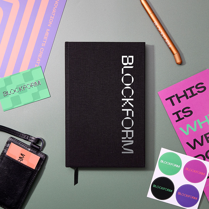 A branded black Hardcover Notebook, Stickers, MOO Twist Pen, Business Card and Flyers on a desk.