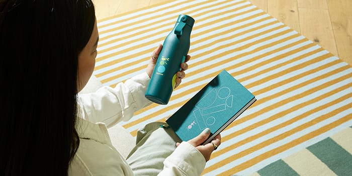 A branded Notebook and Water Bottle being held by a recipient at an event