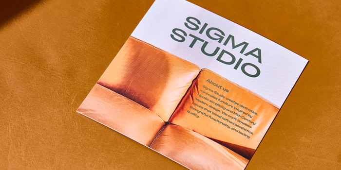 A branded orange and white About Us page on a Postcard placed on a brown surface.