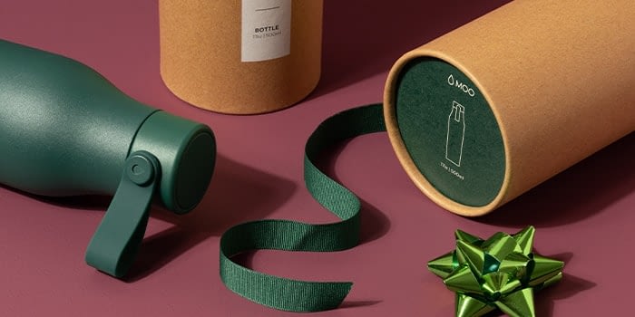 Green reusable water bottle with a carry handle and its cardboard tube packaging with a green ribbon and a gift bow