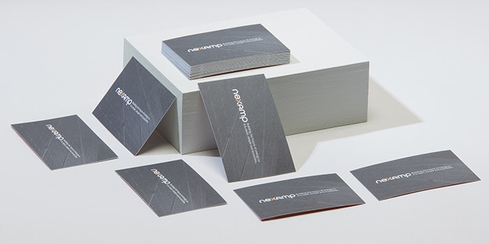 Stacks on grey Nexamp business cards made of recycled cotton