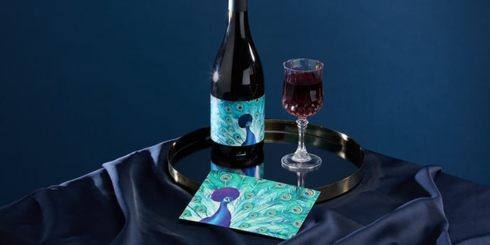 Bottle of McBride Sisters Reserve Collection wine, glass of wine, postcard of an afro peacock