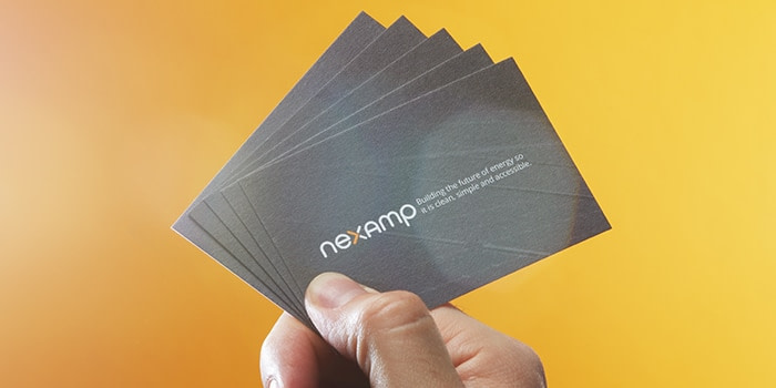 Hand holding grey Nexamp business cards made of recycled cotton