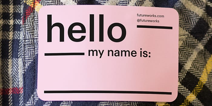 moo brand stickers being used as an icebreaker for trade shows and events. the name tag sticker reads hello my name is, with a space for a fact. the name tag sticker is printed on a business sticker in pink