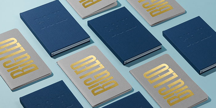 Blue hardcover notebooks and grey custom journals with gold foil text