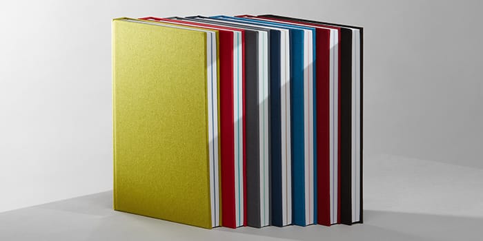 7 hardback notebooks with colorful cloth covers and colored central pages