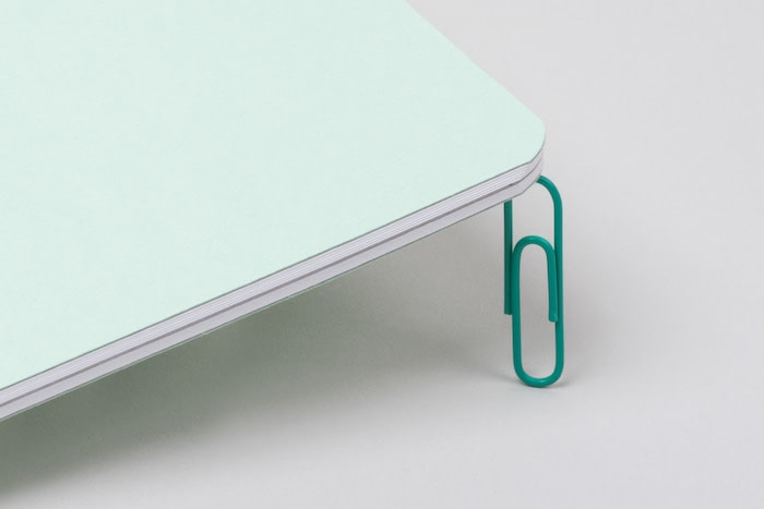 Lightweight mint notebook standing on a green paper clip